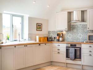 a kitchen with white cabinets and a stove top oven at Tadpole Mews At Frog Hall in Tilston