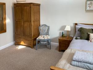 um quarto com uma cama e uma cadeira ao lado de uma cómoda em Tadpole Mews At Frog Hall em Tilston