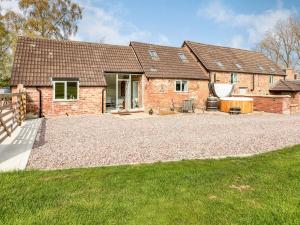 a brick house with a gravel driveway in front of it at Tadpole Mews At Frog Hall in Tilston