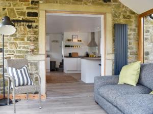 a living room with a couch and a kitchen at Little Plumtree in Addingham