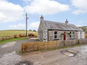 an old stone cottage with a wooden fence at Great Whaup in Culter