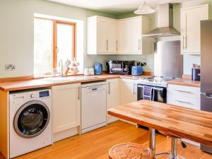 a kitchen with a washing machine and a wooden table at The Milking Parlour in Tutbury