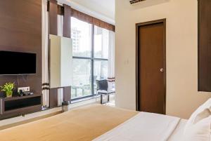 a bedroom with a bed and a tv and a window at Ajantha Komforts, Bengaluru in Bangalore