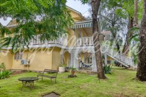 a yellow house with a porch and a table in the yard at Looking Good Surf House San Juan del Sur in San Juan del Sur