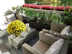 eine Terrasse mit Korbstühlen, einem Tisch und Blumen in der Unterkunft Appt centre ville "Parc Olympe de Gouges" avec garage in Annemasse