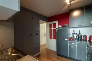 eine Küche mit einem Kühlschrank und einer roten Wand in der Unterkunft Appt centre ville "Parc Olympe de Gouges" avec garage in Annemasse