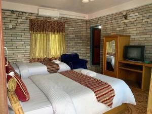 una camera d'albergo con due letti e una tv di Lake Vision Guesthouse a Pokhara