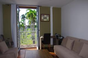 a living room with a couch and a sliding glass door at Hôtel des Palmistes in Cayenne