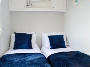 two beds in a room with blue pillows at The Seaview Retreat - Uk35883 in Broughton Mains