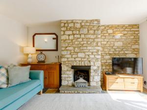 a living room with a blue couch and a stone fireplace at Stocks Cottage in Blockley