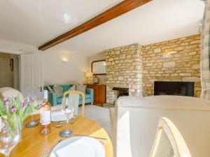 uma sala de estar com uma mesa e uma parede de pedra em Stocks Cottage em Blockley
