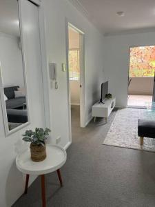 een witte woonkamer met een tafel en een tv bij 2 bedroom modern coastal retreat in Kiama