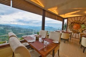 un ristorante con tavolo e sedie e una grande finestra di The Cedar Grand Hotel and Spa a Shimla