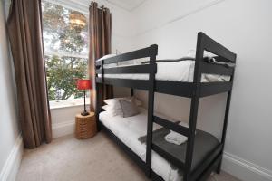 Ce lit superposé noir se trouve dans un dortoir doté d'une fenêtre. dans l'établissement Harrogate Self Catering - West End, à Harrogate
