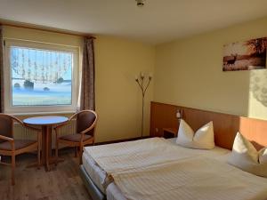 a hotel room with a bed and a table and a window at Hotel und Appartements Jägerhof Rügen in Lancken-Granitz