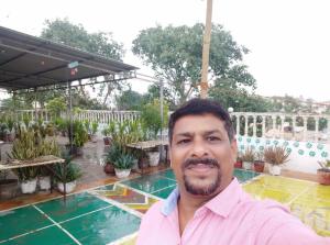 a man in a pink shirt standing in a garden at Hotel Grace in Agra