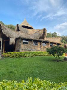 uma casa com um telhado de palha com um quintal em Rancho Ecoturistico el Faro em La Mesa