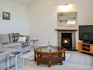 sala de estar con sofá y chimenea en Corrennie School Cottage, en Whitehouse