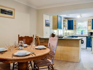 cocina y comedor con mesa de madera y sillas en Corrennie School Cottage, en Whitehouse