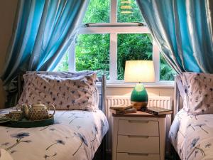 a bedroom with two beds and a window with blue curtains at Corrennie School Cottage in Whitehouse