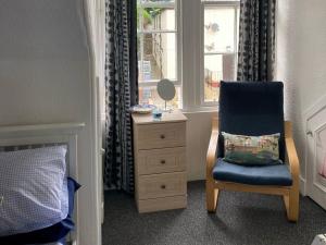 1 dormitorio con silla, vestidor y ventana en Coastal Views Millport en Millport