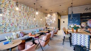 un restaurante con mesas y sillas y una pared con flores en Hideaway Hotel Montestyria Chalets & Suiten, en Mariazell