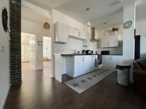 a kitchen and living room with white cabinets and wood floors at Seafield Lodge in Grantown on Spey