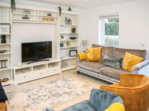 a living room with a couch and a tv at Forget Me Not Cottage in Culross