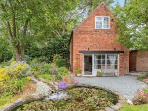 a brick house with a garden and a pond at Owl Cottage in Howell