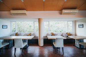 twee tafels en stoelen in een kamer met ramen bij Allia Residence in Nusa Dua