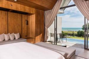 a bedroom with a bed and a view of the ocean at Ana Anan Resort & Villas Pattaya in Na Jomtien