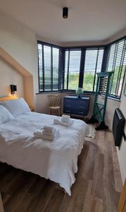 a bedroom with a large white bed and windows at Fairlight Cove in Fairlight