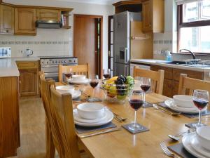 a kitchen with a wooden table with glasses of wine at Westlin in Penpont