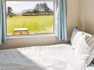 a bed and a window with a view of a field at Ballantines No 29 in Ruan Major