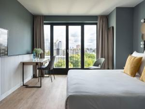 um quarto de hotel com uma cama, uma secretária e uma janela em numa I Arc Rooms & Apartments em Berlim