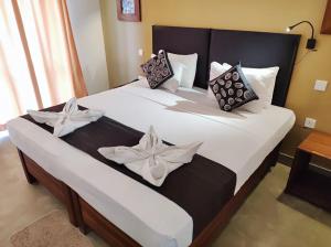 Nil Diya Beach Resort في ماتارا: غرفة نوم بسرير كبير ومخدات بيضاء وسوداء