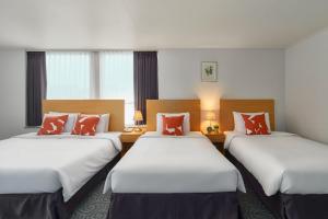 2 łóżka w pokoju hotelowym z białymi i pomarańczowymi poduszkami w obiekcie Hotel Atrium Jongno w Seulu