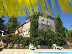 a building with two chairs next to a swimming pool at La Ferme de Jeanne in Saint-Girons