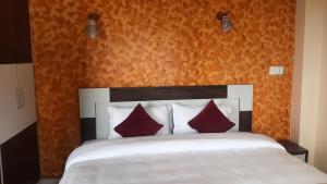 a bedroom with a white bed with red pillows at Dulcify cottage sarangkot in Pokhara