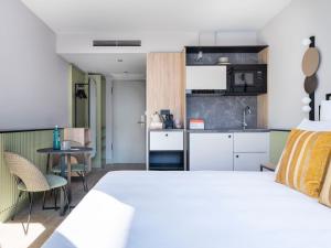 a bedroom with a white bed and a kitchen at numa I Arc Rooms & Apartments in Berlin