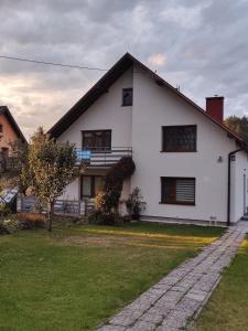 Uma casa branca com um jardim relvado à frente. em Agroturystyka Elżbieta i Juliusz em Muszyna