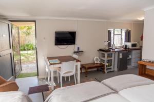 a room with a bed and a table and a kitchen at Vlettershof Guest House in Robertson