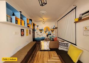 ein Zimmer mit einem Sofa und einem großen Bildschirm in der Unterkunft Young Monk Hostel & Cafe Dharamkot in McLeod Ganj