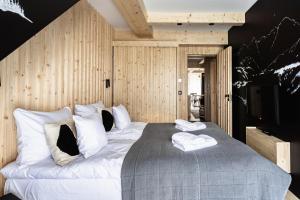 a bedroom with a large bed with two towels on it at ZAKOHOME- Apartamenty Sabały in Zakopane