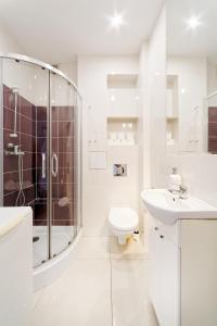 a white bathroom with a shower and a toilet and a sink at Old Town Kanonia Apartments in Warsaw +159 photos