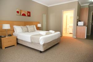 a bedroom with a large white bed with a night stand at Centrepoint Apartments Griffith in Griffith