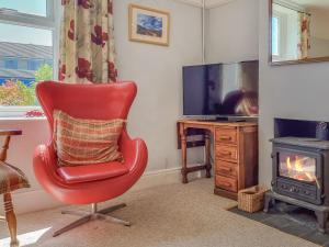 a red chair sitting in a living room with a television at Pear Tree Cottage in Bath