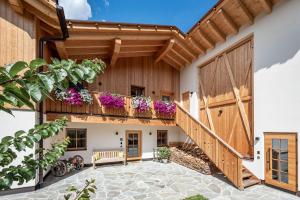 a house with a wooden door and a balcony with flowers at Mein Sonnenhof in San Valentino alla Muta