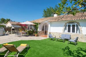 einen Garten mit Stühlen und Tischen und ein Haus in der Unterkunft Casa Bahía de Alcudia in Port d'Alcúdia