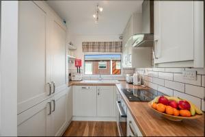 a kitchen with white cabinets and a bowl of fruit on the counter at 5 Norton Park in Dartmouth